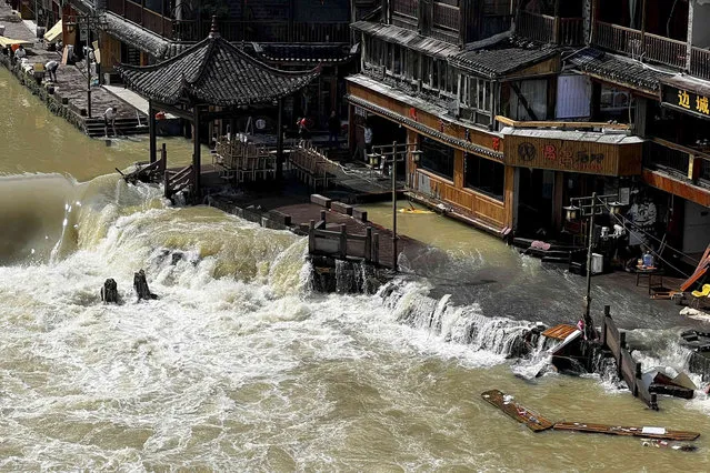 Flood waters sweep through the ancient town of Feng Huang in central China's Hunan province, Saturday, June 4, 2022. State media reported some deaths and missing in flooding in the province. (Photo by AP Photo/China Stringer Network)