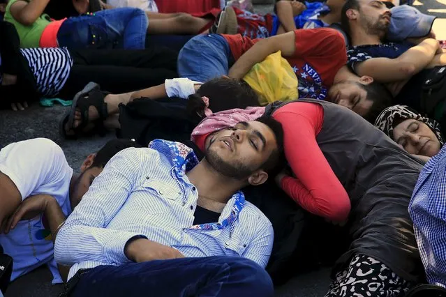 Migrants sleep as they wait to be registered outside the national stadium of the Greek island of Kos, August 12, 2015. (Photo by Alkis Konstantinidis/Reuters)
