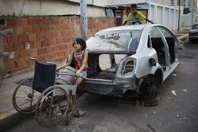 In this November 14, 2019 photo, Ladymar uses her grandmother's wheelchair as a makeshift dolly to transport her water bottle water, in Maracaibo, Venezuela. Opposition leader Juan Guaido, who seeks to oust President Nicolas Maduro, has urged Venezuelans to take to the streets, trying to reignite a movement started early this year. However, few in Maracaibo have responded, despite it being a city hard hit by crisis. (Photo by Rodrigo Abd/AP Photo)