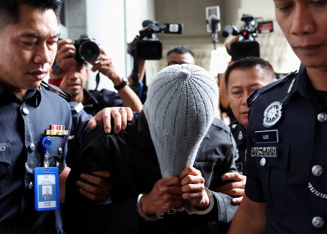 A man linked to Global Ikhwan Service and Business Holdings (GISB) covers his face as he is escorted by police officers after being charged in a court in Putrajaya, Malaysia on September 18, 2024. (Photo by Hasnoor Hussain/Reuters)