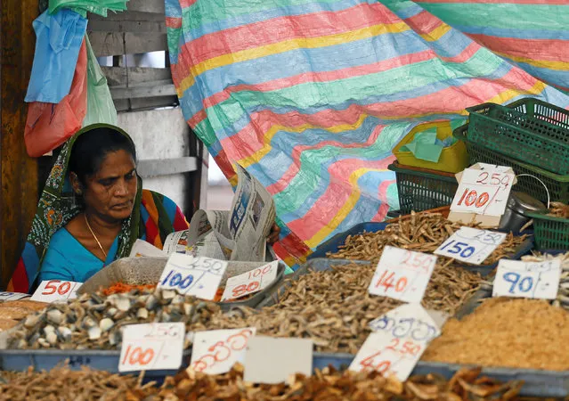 A vendor reads a newspaper at her stall as prices are displayed at a main market in Colombo, Sri Lanka June 24, 2016. (Photo by Dinuka Liyanawatte/Reuters)