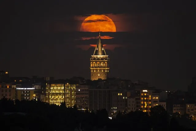 A supermoon rises behind the Galata Tower in Istanbul, Turkey, Tuesday, June 14, 2022. The moon reached its full stage on Tuesday, during a phenomenon known as a supermoon because of its proximity to Earth, and it is also labeled as the “Strawberry Moon” because it is the full moon at strawberry harvest time. (Photo by Emrah Gurel/AP Photo)