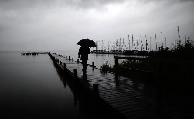 A stroller with umbrella walks on a landing stage  at Lake Steinhuder Meer near Mardorf, northern Germany Friday July 25, 2014. Weather forecasts predict changeable weather for the next few days. (Photo by Alexander Koerner/AP Photo/DPA)