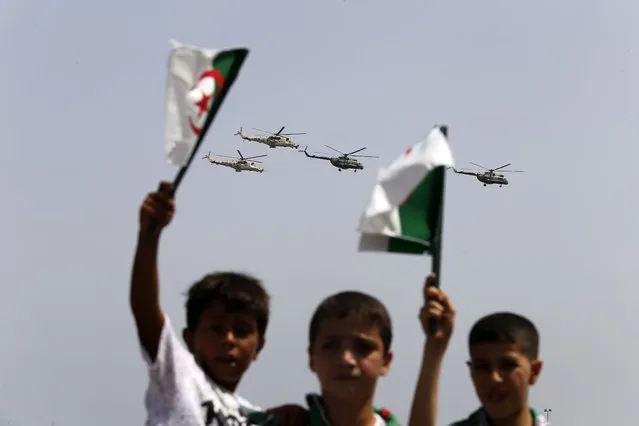 Algerian boys wave their national flag during a military parade to mark the 60th anniversary of Algeria's independence, Tuesday, July 5, 2022 in Algiers. Algeria is celebrating 60 years of independence from France with nationwide ceremonies, a pardon of 14,000 prisoners and its first military parade in years. (Photo by Toufik Doudou/AP Photo)