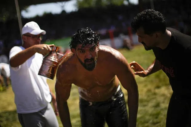 A wrestler is doused in oil by an 'oiler', during the 661st annual Historic Kirkpinar Oil Wrestling championship, in Edirne, northwestern Turkey, Saturday, July 2, 2022. (Photo by Francisco Seco/AP Photo)