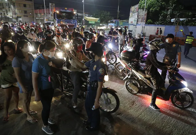 Police check temperatures of people at a checkpoint as part of a precautionary measure against the spread of the new coronavirus at the outskirts of Quezon city in Manila, Philippines Monday March 16, 2020. (Photo by Aaron Favila/AP Photo)