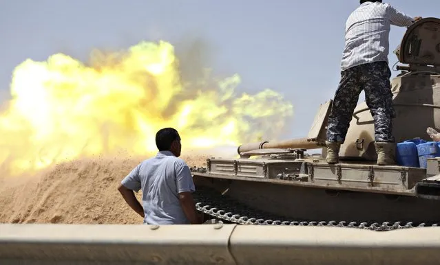 A tank belonging to the Western Shield, a branch of the Libya Shield forces, fires during a clash with rival militias around the former Libyan army camp, Camp 27, in the 27 district, west of Tripoli, August 22, 2014. (Photo by Reuters/Stringer)
