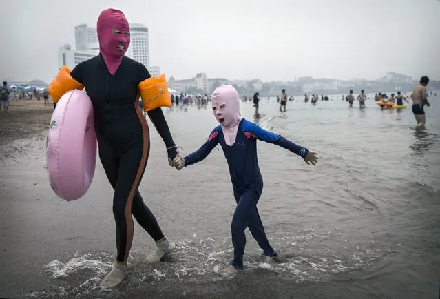 A Chinese woman and her daughter wear face-kinis as they leave the water at the beach on August 21, 2014 on the Yellow Sea in Qingdao, China. (Photo by Kevin Frayer/Getty Images)