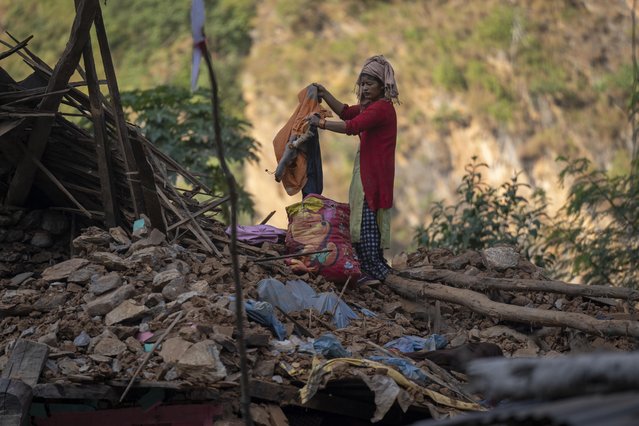 A survivor recovers winter clothes from an earthquake damaged house in Rukum District, northwestern Nepal, Monday, November 6, 2023. The Friday night earthquake in the mountains of northwest Nepal killed more than 150 people and left thousands homeless. (Photo by Niranjan Shrestha/AP Photo)