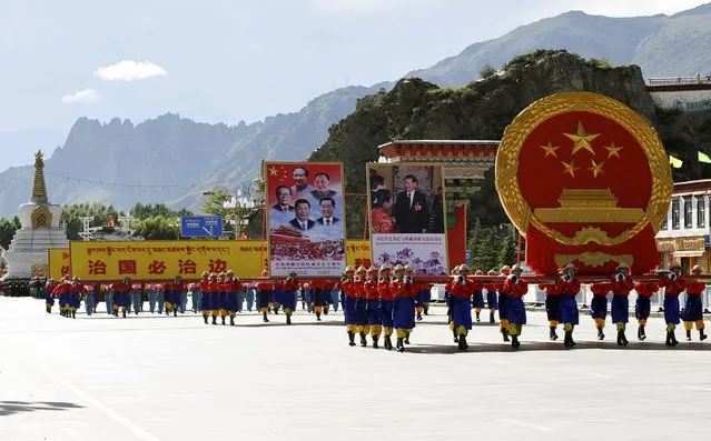 Performers carry a giant Chinese national emblem (R) and pictures of Chinese government leaders including President Xi Jinping, former country leaders Hu Jintao, Jiang Zemin, Deng Xiaoping and Mao Zedong, during the celebration event at the Potala Palace marking the 50th anniversary of the founding of the Tibet Autonomous Region, in Lhasa, Tibet Autonomous Region, China, September 8, 2015. (Photo by Reuters/China Daily)