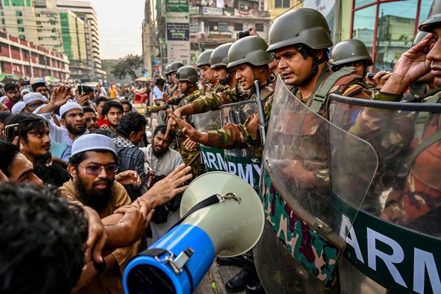 A group of protesters stage a demonstration as Bangladesh Army personnel stand guard in front of the Bangla newspaper Prothom Alo's office in Dhaka on November 25, 2024. Protesters in Bangladesh on November 25 surrounded the offices of one of the few remaining independent newspapers, Prothom Alo, in the latest mass demonstrations demanding that critical media close. (Photo by Munir Uz Zaman/AFP Photo)