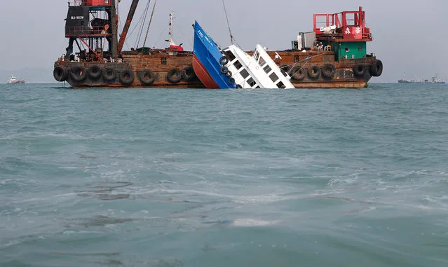 A partially submerged boat is stabilized by the crane of another vessel after it collided with a ferry Monday night near Lamma Island, off the southwestern coast of Hong Kong Island, on October 2, 2012. The boat packed with revelers on a long holiday weekend collided with a ferry and sank off Hong Kong, killing at least 37 people and injuring dozens, authorities said. (Photo by Vincent Yu/AP Photo)