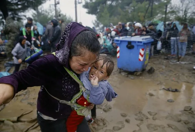 A Syrian refugee cries as she carries her baby walking through the mud to cross the border from Greece into Macedonia during a rainstorm, near the Greek village of Idomeni, September 10, 2015. (Photo by Yannis Behrakis/Reuters)