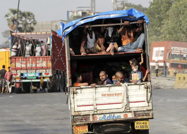 A truck carrying migrant workers leaves for Uttar Pradesh state, on the outskirts of Mumbai, India, Thursday, May 14, 2020. The pandemic has exposed India's deep economic divide as millions of migrant workers have left Indian cities with luggage bags perched on their heads and children in their arms, walking down highways in desperate attempts to reach the countryside. (Photo by Rajanish Kakade/AP Photo)