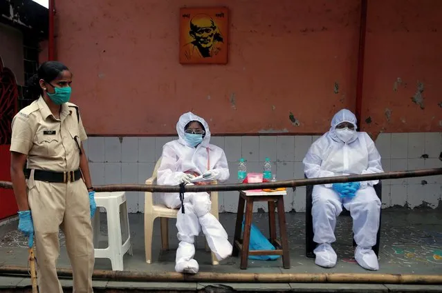 Healthcare workers wait next to a temple, to test residents of Dharavi, one of Asia's largest slums, during an extended lockdown to slow the spread of the coronavirus disease (COVID-19), in Mumbai, India, May 28, 2020. (Photo by Francis Mascarenhas/Reuters)