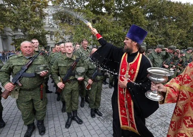 An Orthodox priest conducts a service for reservists drafted as part of the partial mobilisation, during a ceremony of their departure for military bases, in Sevastopol, Crimea on September 27, 2022. (Photo by Alexey Pavlishak/Reuters)