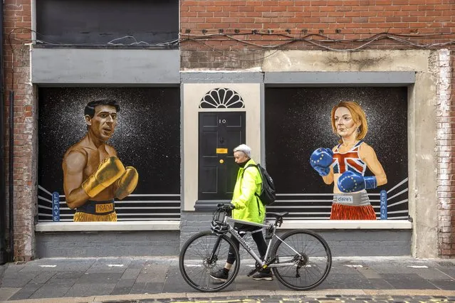 A women walks past a mural on Hill Street in Belfast on Tuesday, August 16, 2022, by Ciaran Gallagher Art, commissioned by local bar owner Willie Jack, showing conservative party candidates, Rishi Sunak and Liz Truss as two boxers about to fight it out to be the UK Prime Minister. (Photo by Liam McBurney/PA Images via Getty Images)