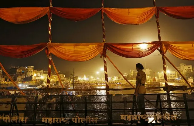 A policewoman stands guard as Hindu devotees take a dip in the waters of Godavari river during the second “Shahi Snan” (grand bath) at Kumbh Mela or Pitcher Festival in Nashik, India, September 13, 2015. (Photo by Adnan Abidi/Reuters)