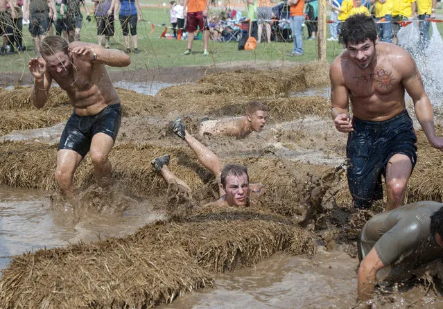 Participants make their way through the Electroshock Therapy obstacle during the Tough Mudder at Michigan International Speedway on Saturday, September 20, 2014. The 11.7 mile course is billed as “probably the toughest event on the planet”. (Photo by J. Scott Park/AP Photo/The Citizen Patriot/MLive.com)