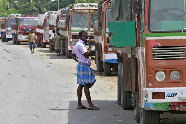 A truck driver brushes his teeth next to his parked truck while waiting to get his loads cleared to cross a checkpoint at the Commercial Taxes Department check post at Walayar in Palakkad district in southern Indian state of Kerala, India, September 5, 2015. At the Walayar checkpoint in southern India, lines of idle trucks stretch as far as the eye can see in both directions along the tree-lined interstate highway, waiting for clearance from tax inspectors that can take days to complete. (Photo by Sivaram V/Reuters)