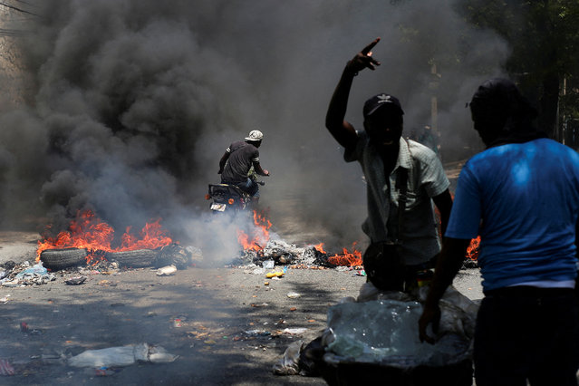 A motorcyclist rides past a burning barricade during a protest against insecurity, in Port-au-Prince, Haiti on March 19, 2025. (Photo by Jean Feguens Regala/Reuters)