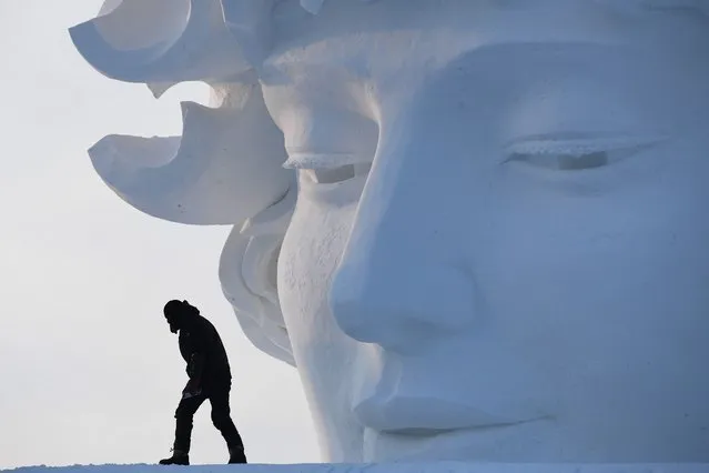 A worker walks past a snow sculpture before the opening of the annual Harbin Ice and Snow Sculpture Festival in Harbin in China's northeast Heilongjiang province on January 5, 2018. The festival attracts hundreds of thousands of visitors annually. (Photo by Greg Baker/AFP Photo)