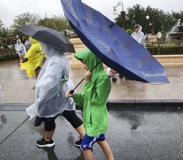 Winds blow an umbrella inside-out as guests leave the Magic Kingdom at Walt Disney World in Lake Buena Vista, Fla., Wednesday, November 9, 2022, as conditions deteriorate with the approach of Hurricane Nicole. All 4 Disney parks in Central Florida closed early Wednesday because of the impending storm. (Photo by Joe Burbank/Orlando Sentinel via AP Photo)
