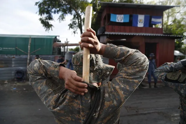 A soldier places a hand made, wooden stick into the back of his uniform as he stands guard in El Cinchado, Guatemala, on the border with Honduras, Friday, October 2, 2020. Guatemala vowed to detain and return members of a new caravan of about 2,000 migrants that set out from neighboring Honduras in hopes of reaching the United States, saying they represent a health threat amid the coronavirus pandemic. (Photo by Moises Castillo/AP Photo)