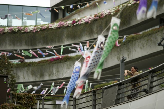 A woman sings a song near carp-shaped windsocks, or “koinobori”, at the Skytree tower in Tokyo, April 30, 2024. Koinobori were installed to mark Children's Day celebrated on May 5. (Photo by Hiro Komae/AP Photo)