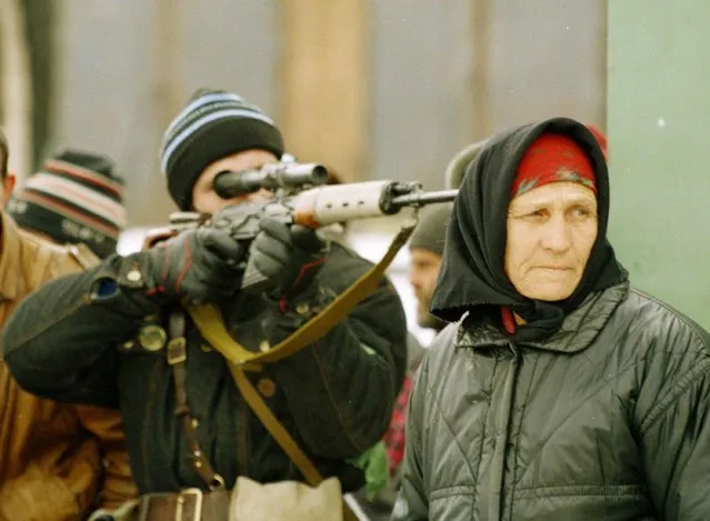 In this  January 25, 1995 file photo, a Chechen sniper takes aim as a woman looks on after a Russian sniper took a pot shot at a street market on the southern outskirts of Grozny. (Photo by Karsten Thielker/AP Photo/File)