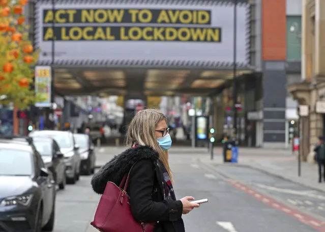 A woman wearing a face mask walks in Manchester, England, Monday, October 19, 2020. Britain’s government says discussions about implementing stricter restrictions in Greater Manchester must be completed Monday because the public health threat caused by rising COVID-19 infections is serious and getting worse. (Photo by Peter Byrne/PA Wire via AP Photo)