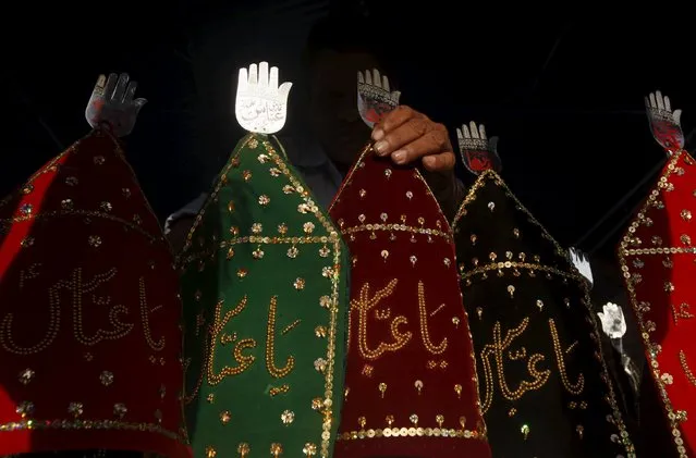 A man adjusts a religious motif put up for sale outside a shop ahead of the Shi'ite Muslims festival of Ashura in Karachi, Pakistan October 14, 2015. Ashura, which falls on the 10th day of the Islamic month of Muharram, commemorates the death of Imam Hussein, grandson of Prophet Mohammad, who was killed in the 7th century battle of Kerbala. (Photo by Athar Hussain/Reuters)