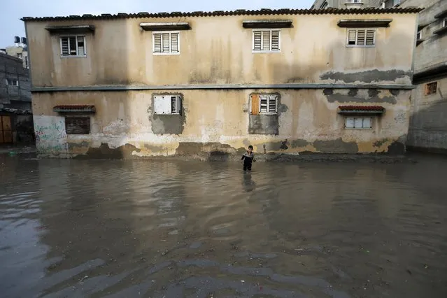 A Palestinian boy walks along a street flooded by rain water in Khan Younis in the southern Gaza Strip, November 9, 2015. (Photo by Ibraheem Abu Mustafa/Reuters)