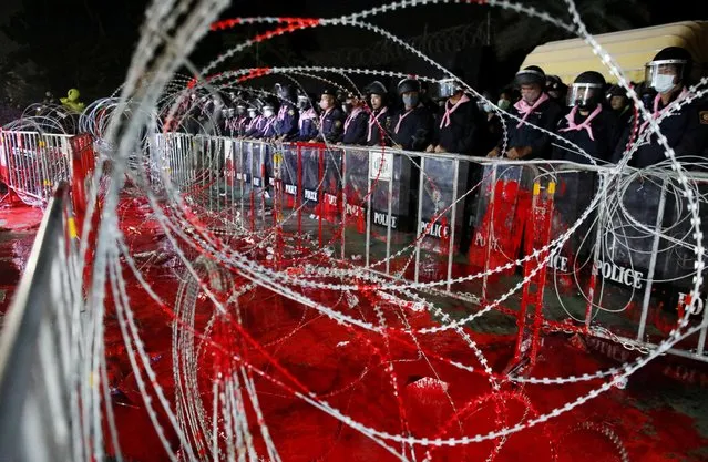 Riot police officers stand guard behind barb wires covered with red paint during a pro-democracy rally demanding Prime Minister Prayuth Chan-ocha to resign and reforms to the monarchy, at 11th Infantry Regiment, in Bangkok, Thailand, November 29, 2020. (Photo by Soe Zeya Tun/Reuters)