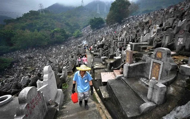 People walk through the Diamond Hill Cemetery in Hong Kong on April 5, 2023 as they visit cemeteries to honour their ancestors during the annual Tomb Sweeping Day, known locally in Hong Kong as Ching Ming. (Photo by Peter Parks/AFP Photo)