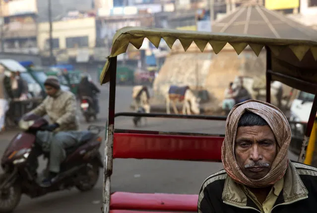 A rickshaw puller waits for customers outside a metro railway station, in New Delhi, India, Monday, December 29, 2014. (Photo by Manish Swarup/AP Photo)