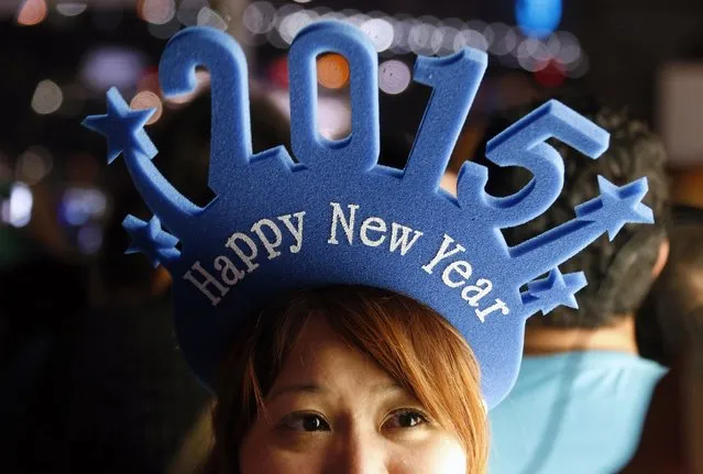 A woman wears a head band displaying 2015 as she waits for the annual New Year fireworks display on Sydney Harbour December 31, 2014. More than 10,000 aerial fireworks, 25,000 shooting comets and 100,000 pyrotechnic effects will be used during this year's Sydney Harbour New Year's Eve show, with an estimated 1.2 million people watching from along the harbour foreshore, local media reported. (Photo by David Gray/Reuters)