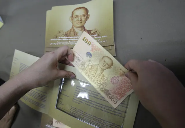 A mourner inserts a commemorative banknote of Thai King Bhumibol Adulyadej in Bangkok, Thailand, Tuesday, October 18, 2016. For Thailand's royalists – and there are millions of them – King Bhumibol Adulyadej will probably long remain embedded as a potent, father-like figure who guided them through turbulent decades and espoused ideals of national harmony, labor on behalf of the poor and the virtues of an agrarian society vanishing in the wake of headlong modernization. (Photo by Sakchai Lalit/AP Photo)