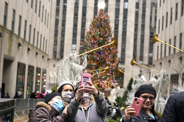 People take pictures of themselves with the Rockefeller Center Christmas tree in New York on Christmas day, Friday, December 25, 2020. The coronavirus upended Christmas traditions, but determination and imagination kept the day special for many. (Photo by Seth Wenig/AP Photo)