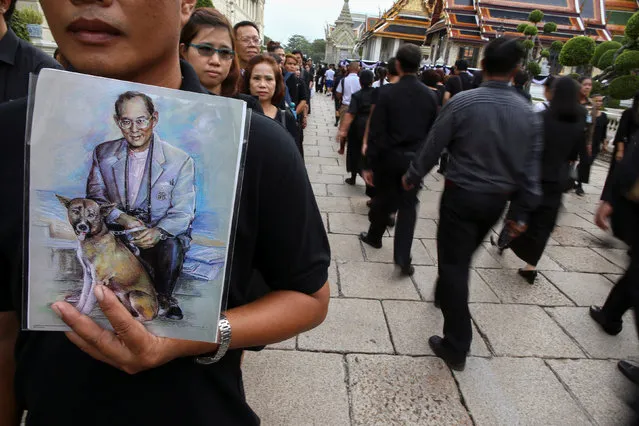 Mourners hold up pictures of Thailand's late King Bhumibol Adulayadej as they walk in line into the Throne Hall at the Grand Palace for the first time to pay respects to his body that is kept in a golden urn in Bangkok, Thailand, October 29, 2016. (Photo by Athit Perawongmetha/Reuters)