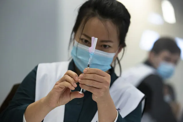 An employee of the Municipal Health Service GGD prepares a Pfizer-BioNTech COVID-19 vaccine to be administered to a health care worker at a coronavirus vaccination facility in Houten, central Netherlands, Friday, January 8, 2021. (Photo by Peter Dejong/AP Photo)
