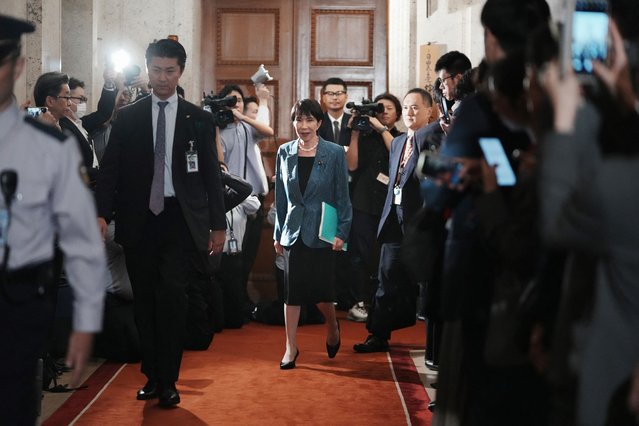 Japan's ruling Liberal Democratic Party (LDP) President Sanae Takaichi (C) walks before signing a policy agreement with Japan Innovation Party (JIP) leader Hirofumi Yoshimura at the Diet in Tokyo on October 20, 2025. Japan's ruling LDP and its junior partner signed a coalition deal on October 20, paving the way for Sanae Takaichi to become the country's first woman premier. (Photo by Kazuhiro Nogi/AFP Photo)