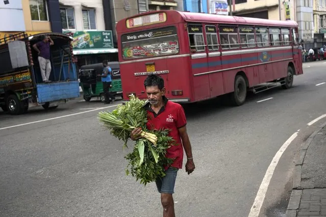A man walks towards a market place carrying curry leaves in Colombo, Sri Lanka, Tuesday, March 21, 2023.(Photo by Eranga Jayawardena/AP Photo)