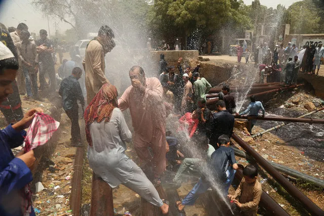People cool off around punctured water supply lines as heatwave continue in Karachi, Pakistan, 22 May 2018. According to reports at least 65 people have been killed due to heatwave as temperatures reached up to 44 degrees Celsius. (Photo by Rehan Khan/EPA/EFE)