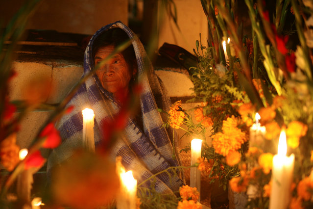 A woman sits next to a grave on the Day of the Dead by paying homage to her dead relatives at  Santa Maria Atzompa cemetery in Oaxaca Mexico, November 1, 2016. (Photo by Jorge Luis Plata/Reuters)