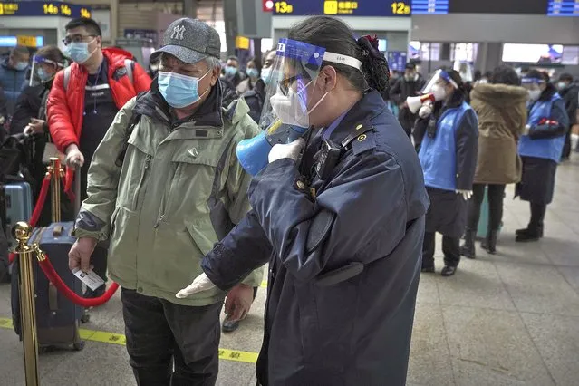 A worker wearing a face mask and face shield to help curb the spread of the coronavirus uses a loud speaker to ask a masked passenger to keep distancing in the line at the South Train Station in Beijing, Thursday, January 28, 2021. Efforts to dissuade Chinese from traveling for Lunar New Year appeared to be working. Beijing's main train station was largely quiet on the first day of the travel rush and estimates of passenger totals were smaller than in past years. (Photo by Andy Wong/AP Photo)