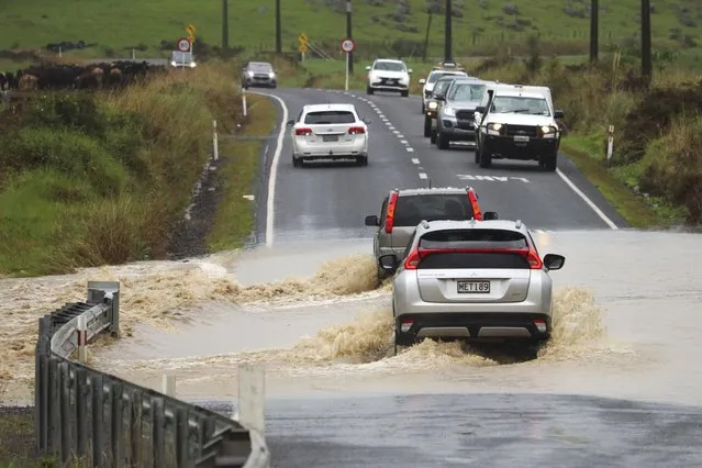 Cars move through a flooded road near Waimate, north of Auckland, New Zealand, Tuesday, May 9, 2023. Authorities in Auckland have declared a state of emergency as flooding again hits New Zealand's largest city. (Photo by Peter de Graaf/Northern Advocate via AP Photo)