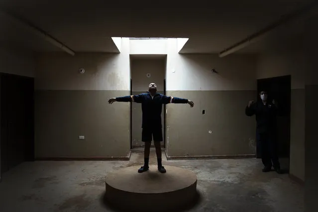 An inmate of the Educational Center of Itagua for juvenile offenders, clowns around on a platform where the statue of a saint used to be, as a guard talks on his radio in Itagua, Paraguay, Monday, September 14, 2020. Inmates are demanding that visiting privileges that have been suspended since the new coronavirus pandemic started seven months ago, be restored. (Photo by Jorge Saenz/AP Photo)