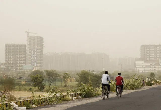 Cyclists pedal on a road enveloped by a thick haze of dust in Greater Noida, on the outskirts of New Delhi, India, Thursday, June 14, 2018. The Indian capital region experienced severe levels of pollution for the third straight day on Thursday. Over the past two years, New Delhi has earned the dubious distinction of being one of the world's most polluted cities. (Photo by R.S. Iyer/AP Photo)
