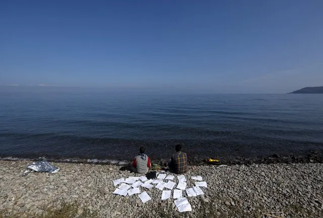 Two Syrian refugee students dry their documents on a beach on the Greek island of Lesbos October 19, 2015. (Photo by Yannis Behrakis/Reuters)